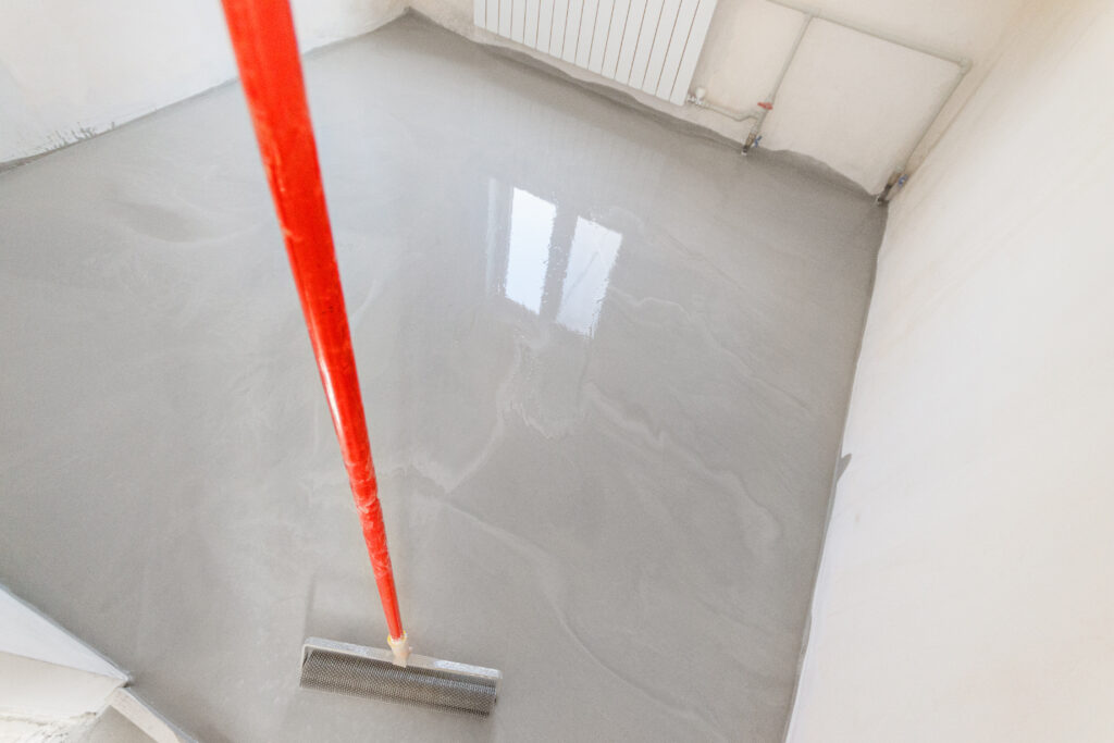 Professional using spiked roller to level epoxy floor