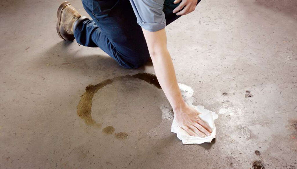 man cleaning oil spill from garage floor